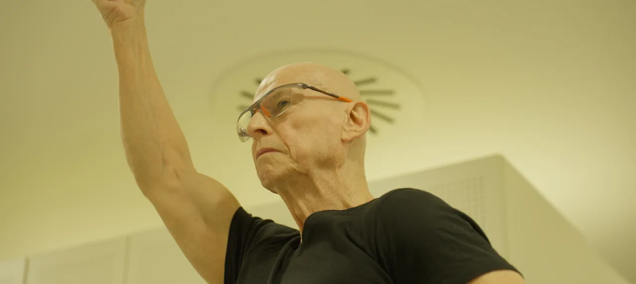 Detailní záběr na stříbrné vlasy a profil obličeje legendárního akrobata.