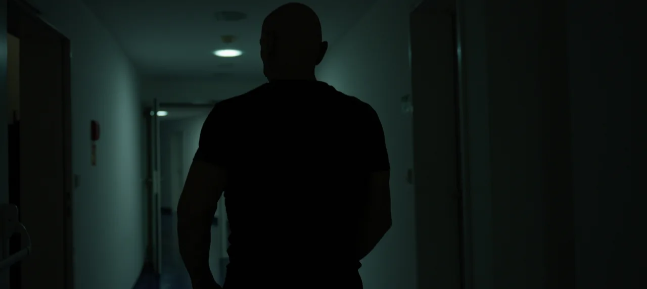 Detail na objektiv filmové kamery odrážející postavu cvičícího Boba Divílka.